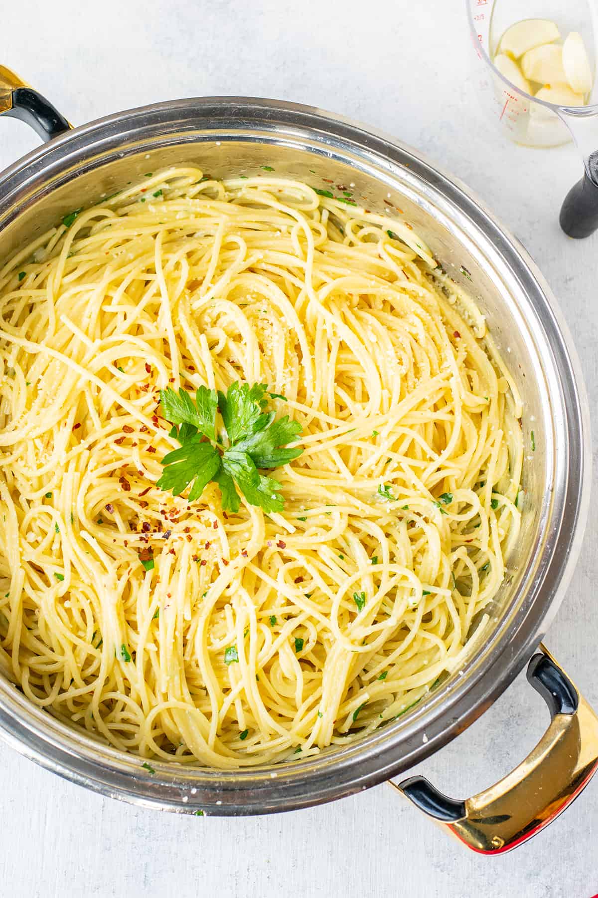 cooked spaghetti in pan with parsley and pepper flakes