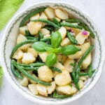 prepared italian potato salad with green beans in a bowl with basil on top