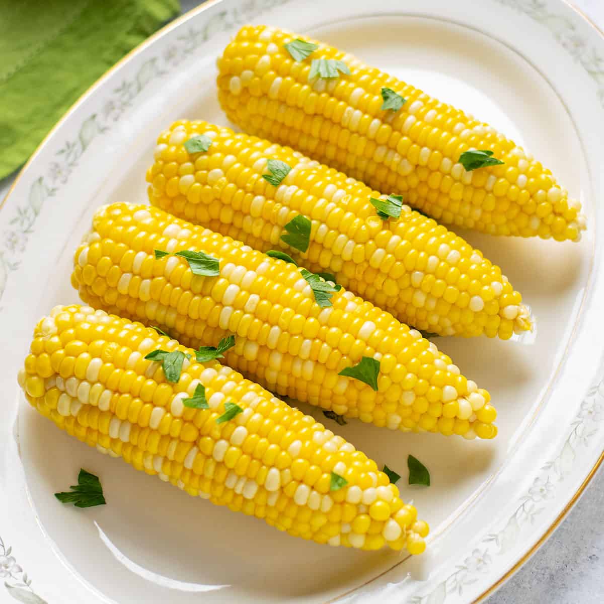 four ears of steamed corn on the cob on a platter