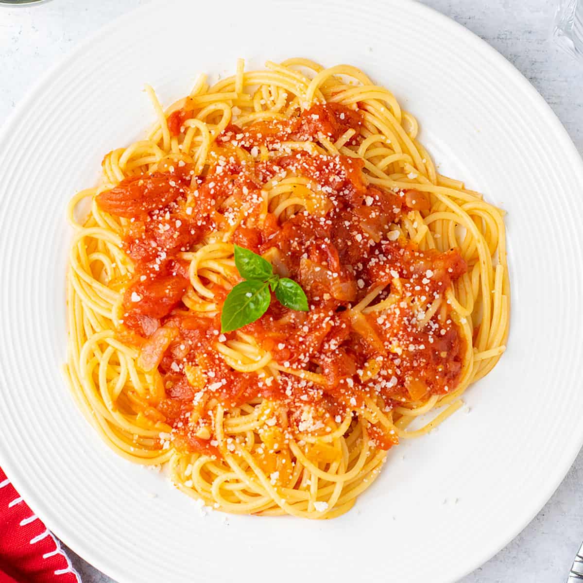 plate of spaghetti topped with sauce and cheese. garnished with basil.