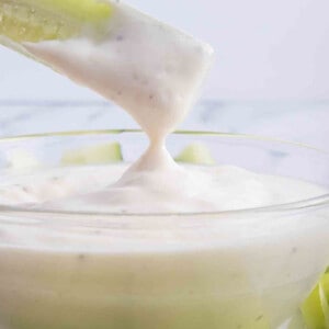 Cucumber stick being dipped in a bowl of homemade ranch dressing