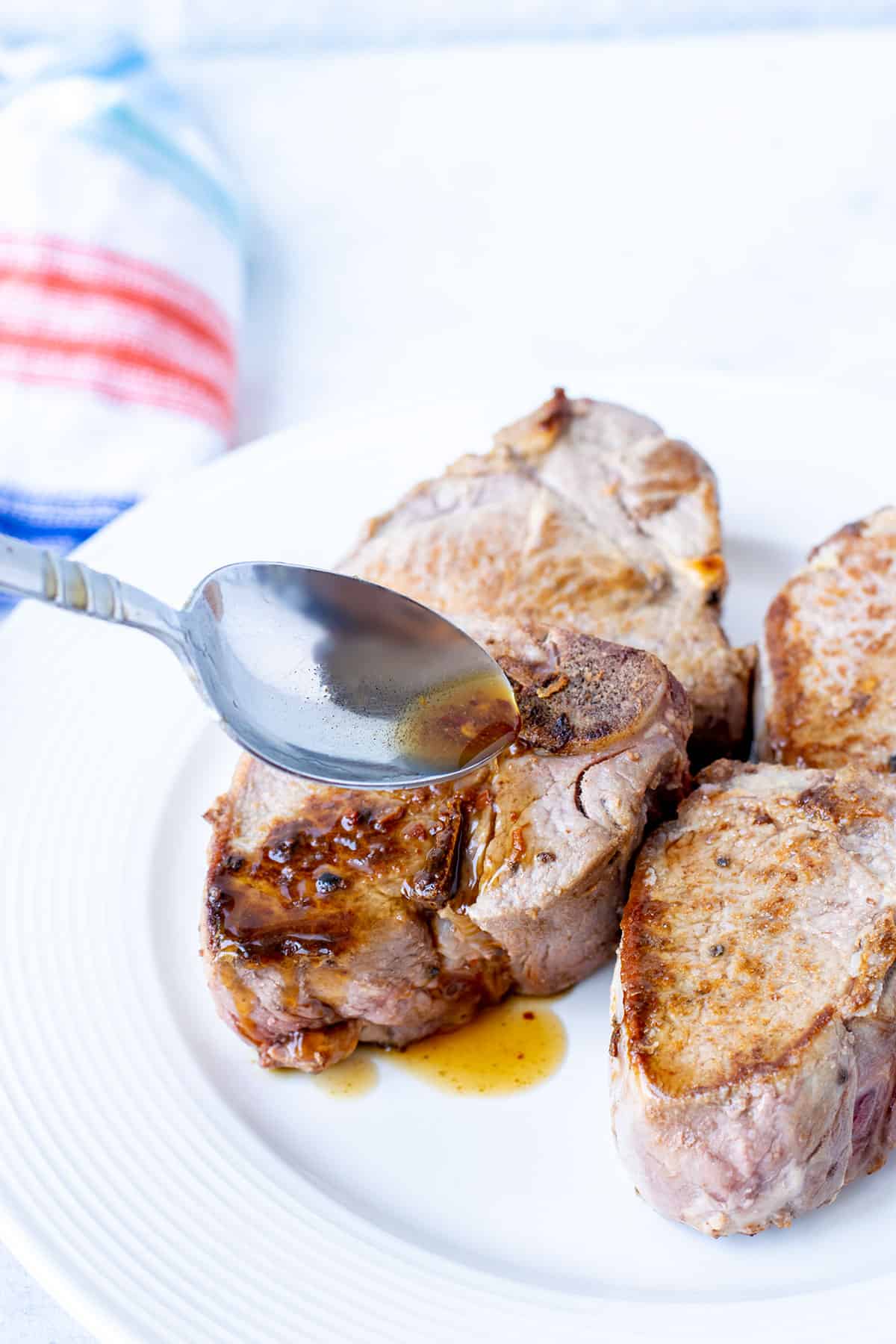 Carolina Vinegar BBQ Sauce poured over lamb chops with a spoon.