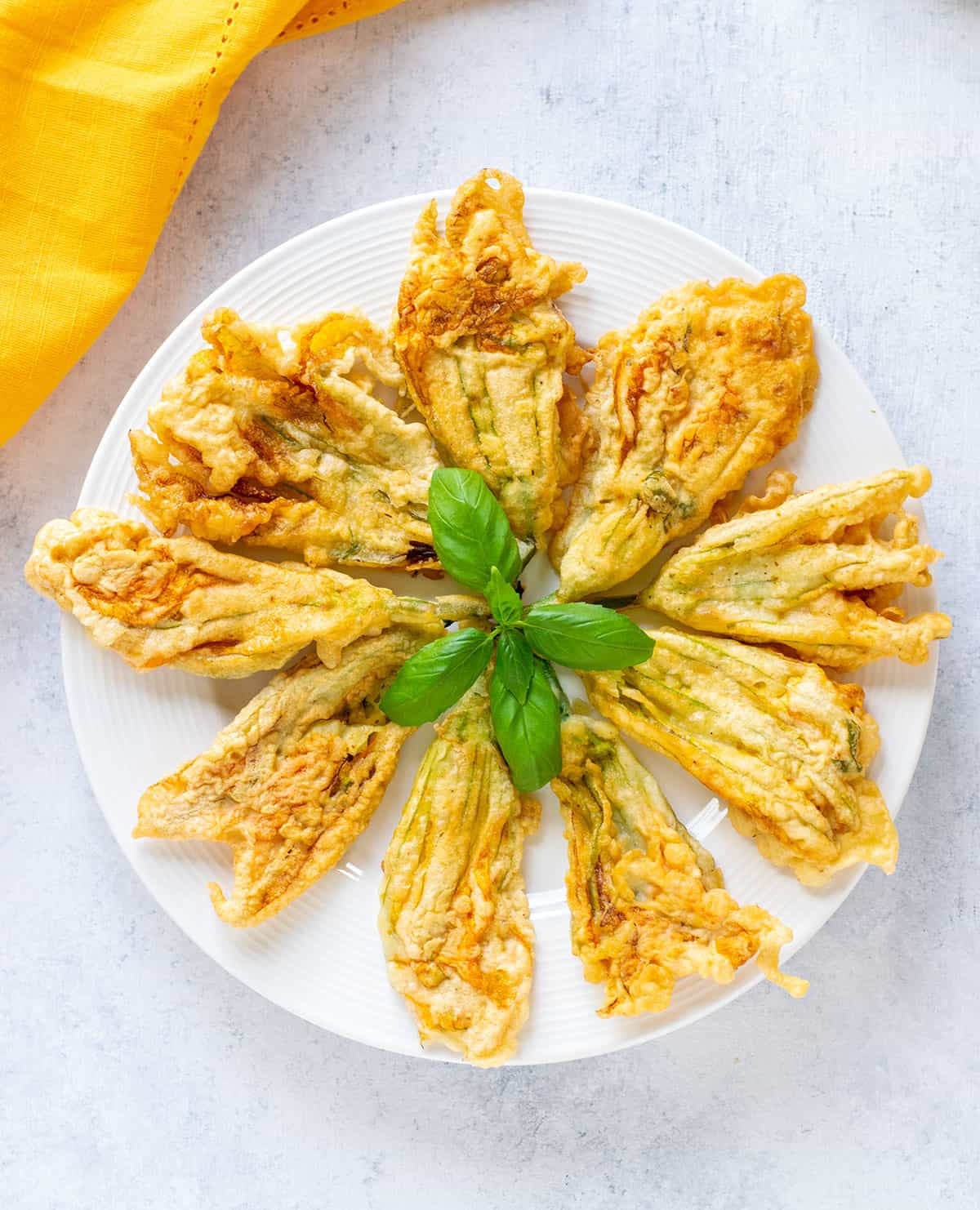 plate of fried zucchini flowers with basil on top.