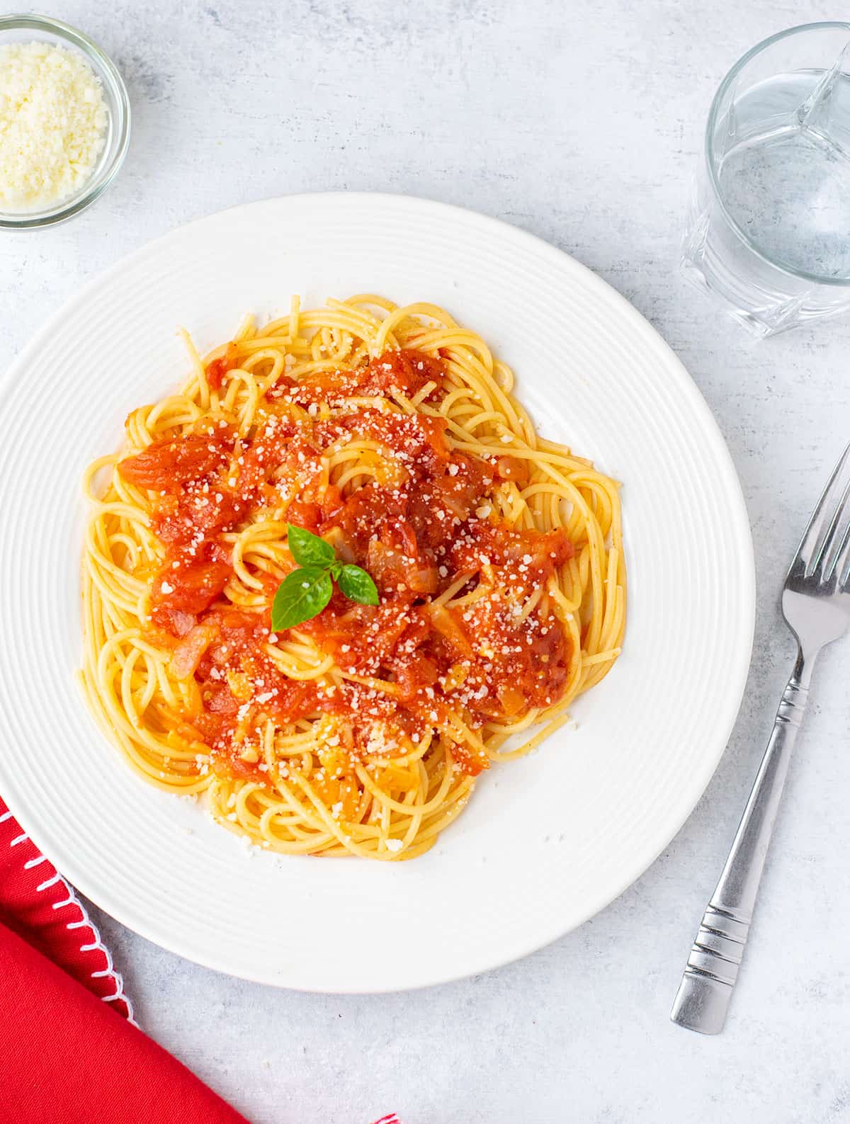 plate of spaghetti topped with sauce and cheese. garnished with basil.