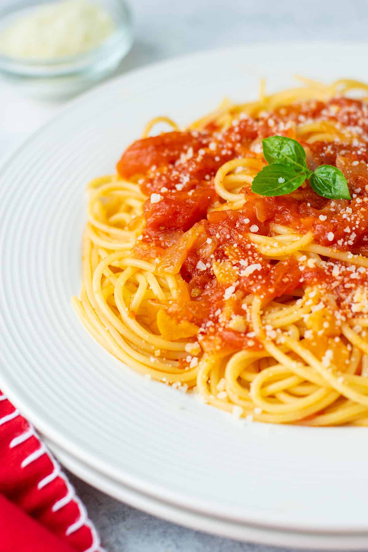 plate of spaghetti topped with sauce and cheese. garnished with basil.