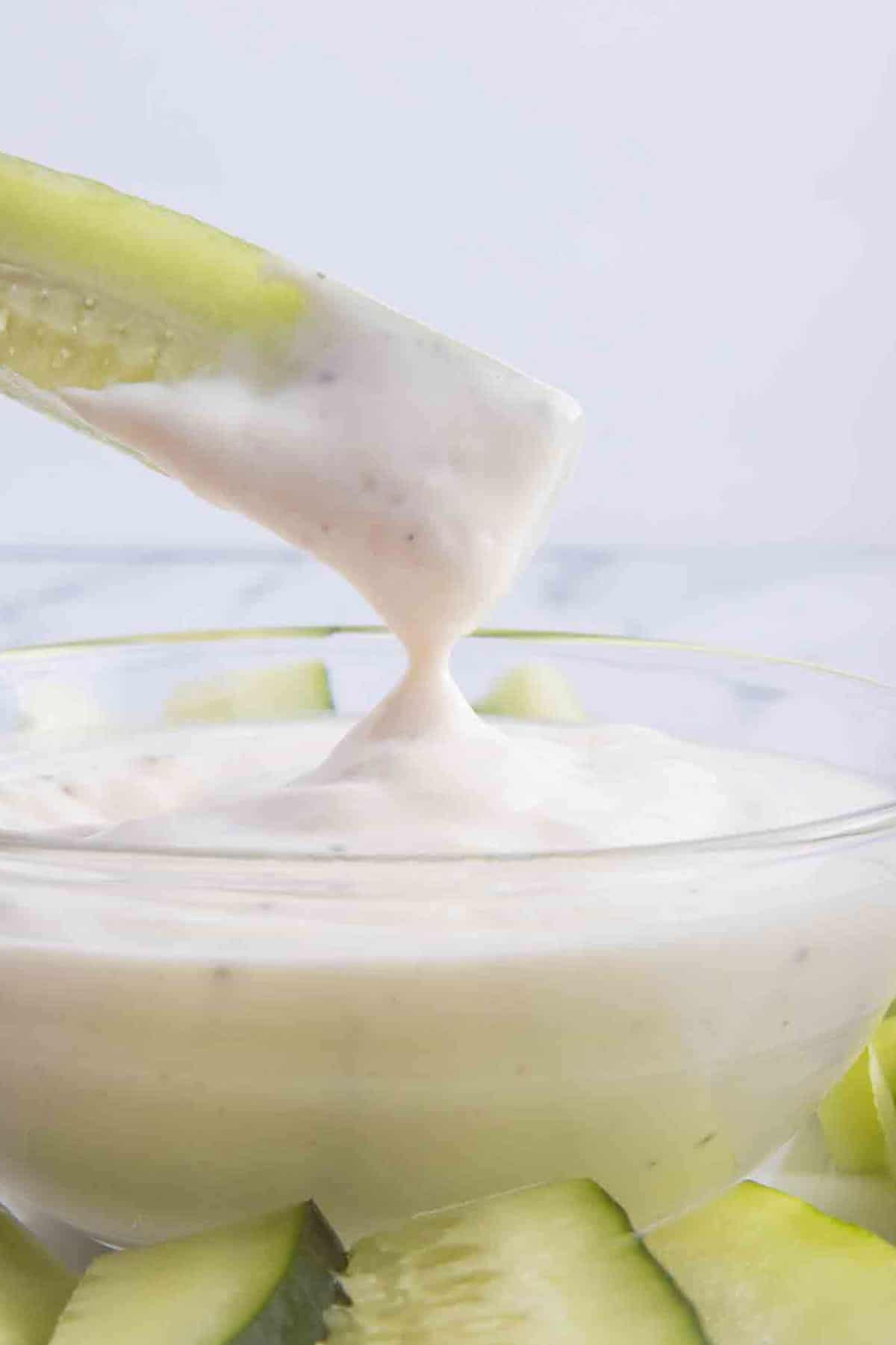 cucumber stick being dipped in a bowl of homemade ranch