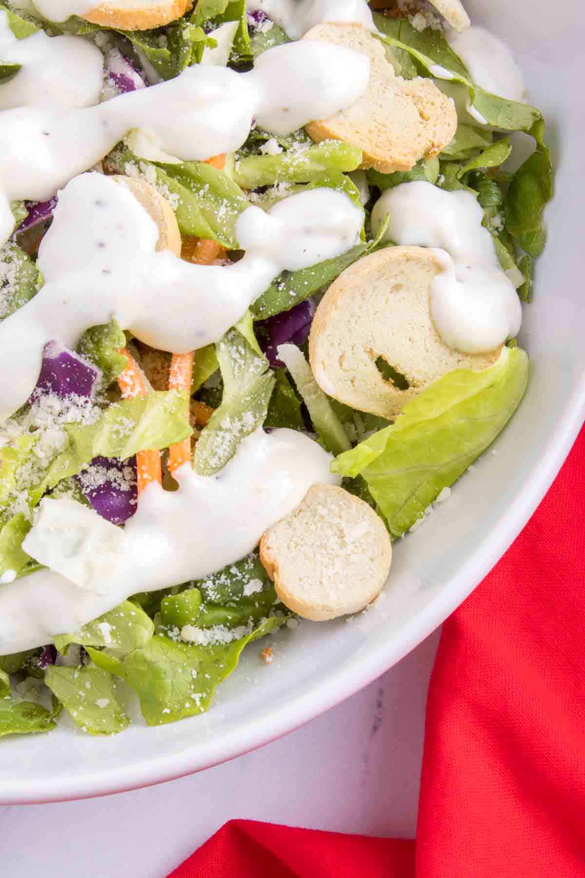 ranch dressing drizzled over salad with croutons and carrots