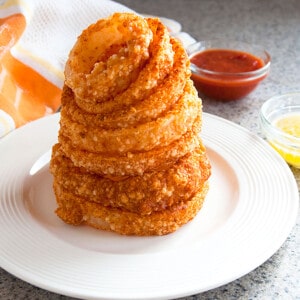 tower of onion rings with dipping sauces in the background.