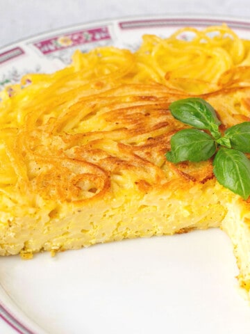 fried spaghetti pie on plate with a couple of pieces missing.