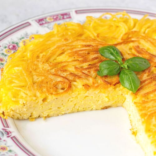 fried spaghetti pie on plate with a couple of pieces missing.