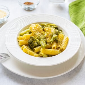 bowl of prepared pasta with broccoli topped with parmesan cheese