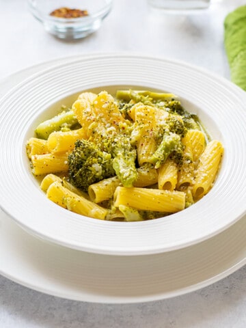 bowl of prepared pasta with broccoli topped with parmesan cheese