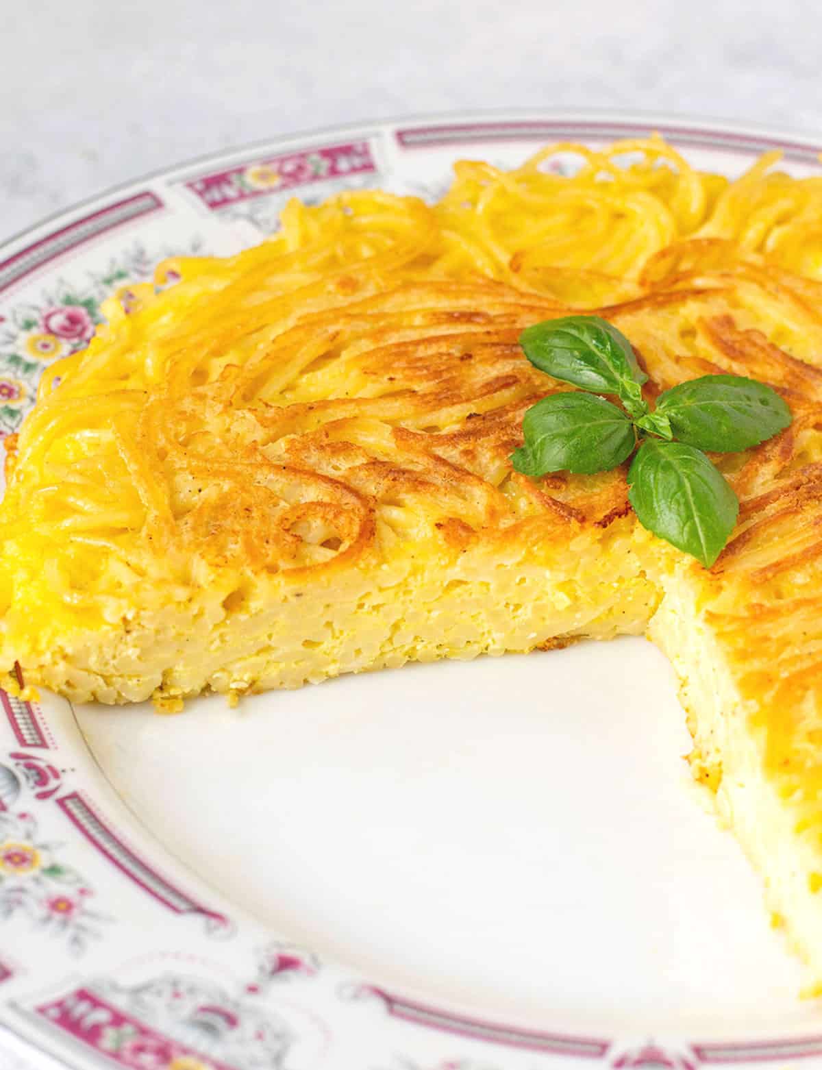 prepared spaghetti frittata with a slice cut out of it.