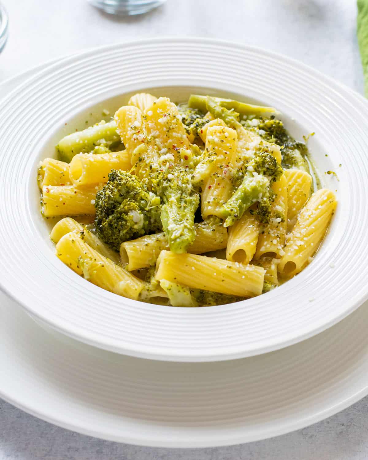 bowl of prepared pasta with broccoli topped with Parmesan cheese.