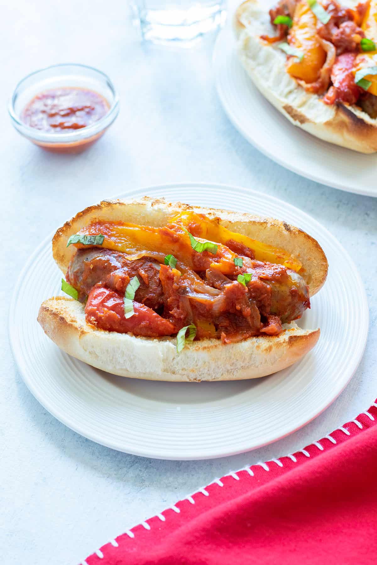 sausage and peppers sandwich topped with sauce and basil