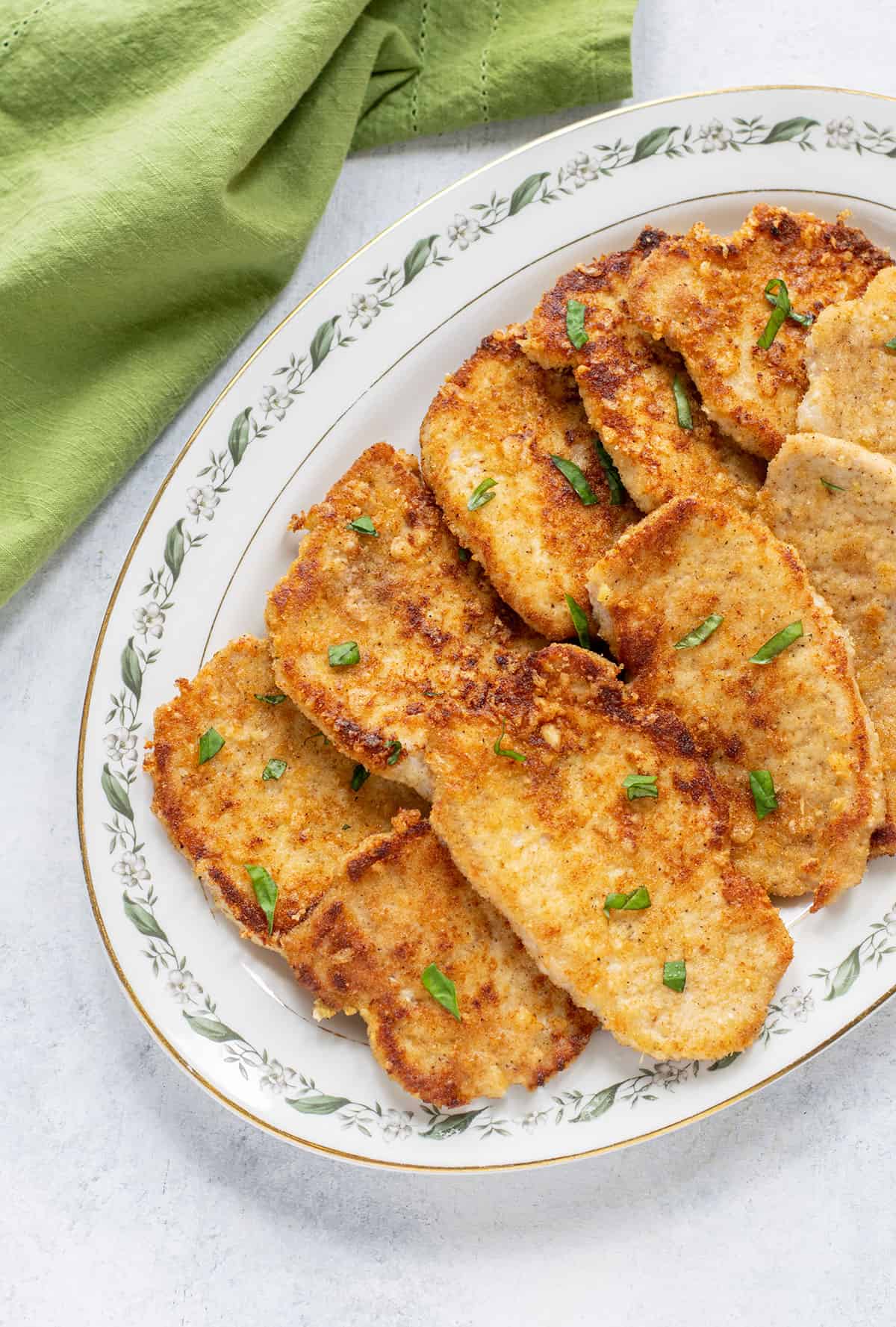 platter of breaded pork chops garnished with basil