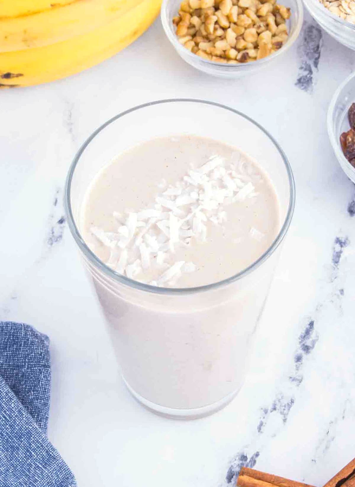 oatmeal smoothie in a glass garnished with coconut flakes.