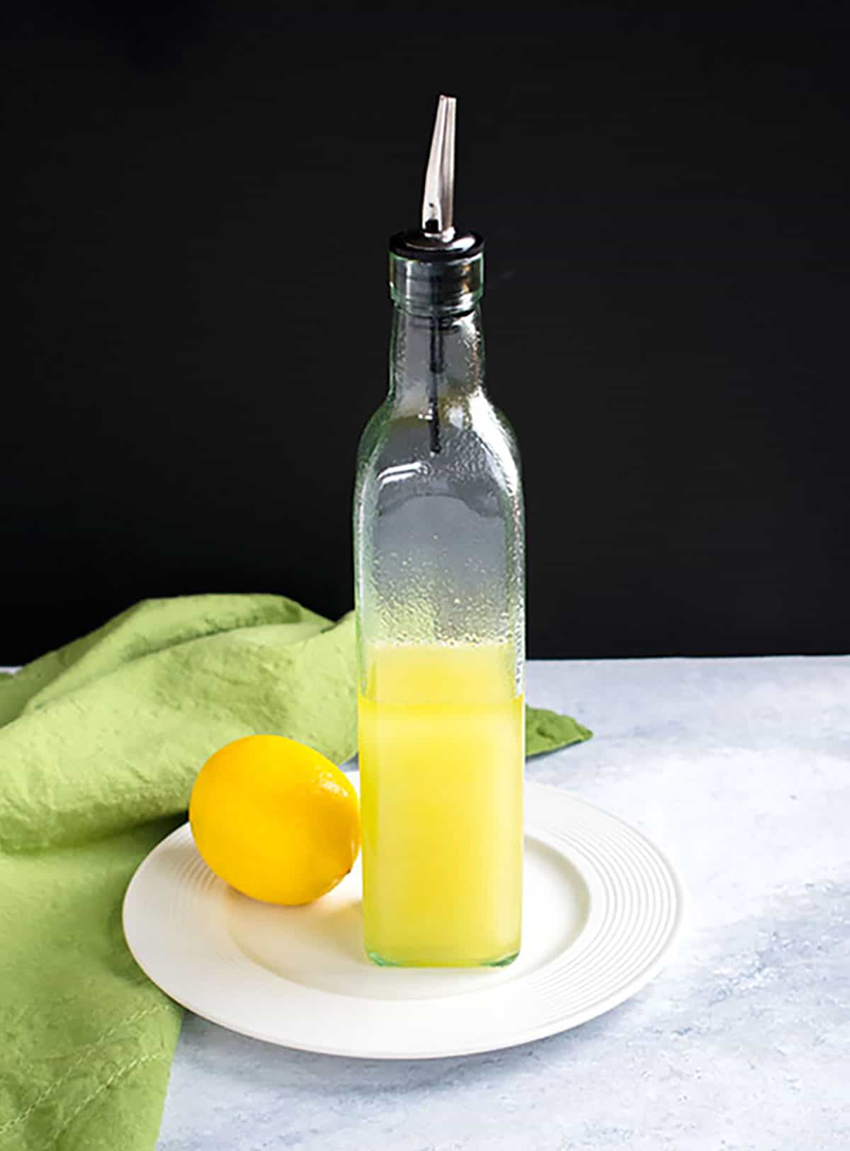 bottle of lemon olive oil on a plate with a lemon