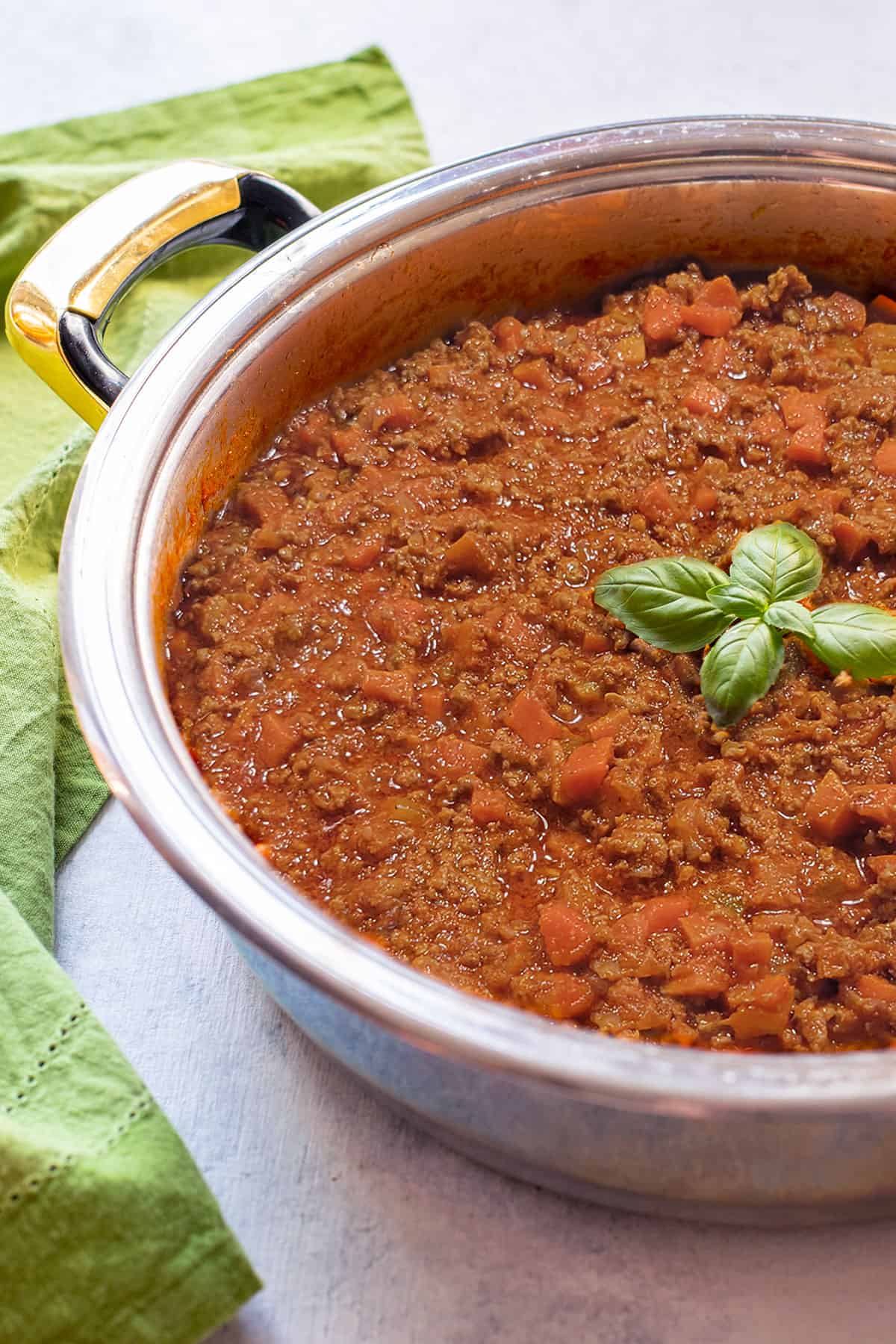 pan of beef bolognese with sausage garnished with basil