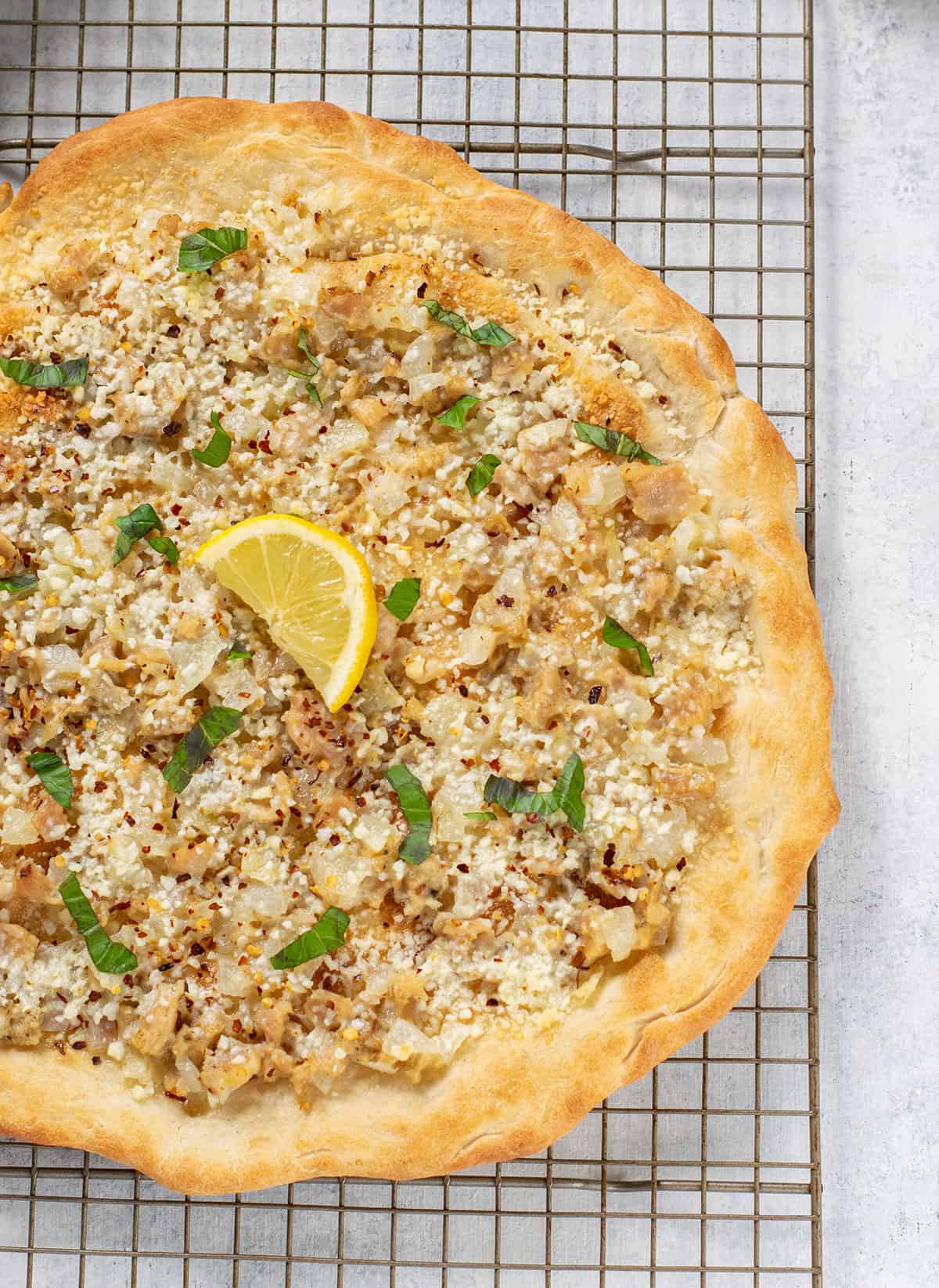 white clam pizza on a cooling rack garnished with lemon and basil