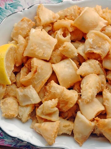 prepared calamari on a platter with a lemon wedge