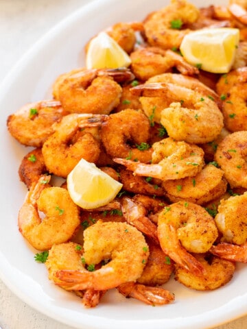 platter of breaded fried shrimp with lemon wedges