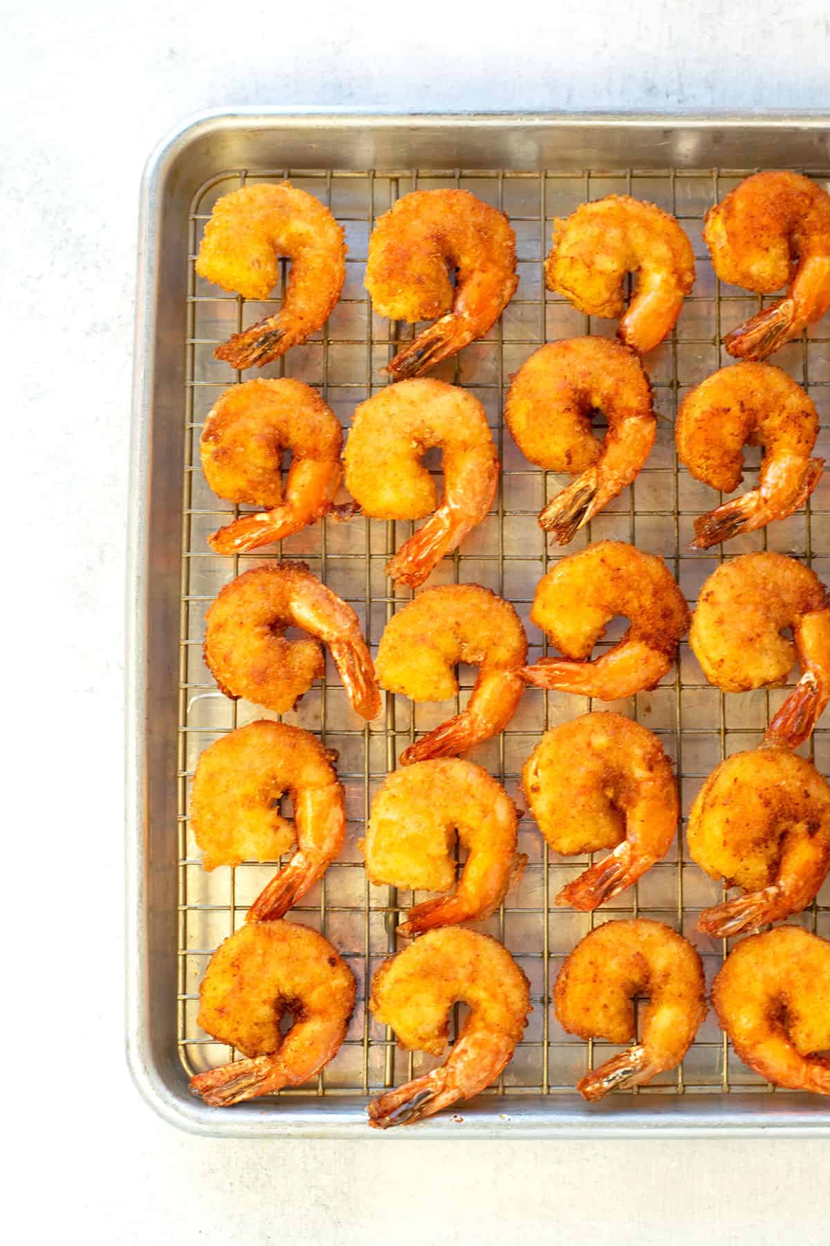 breaded fried shrimp on a rack in a sheet pan