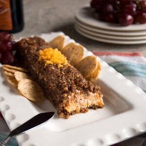 pecan coated cheese log on a platter with crackers and grapes