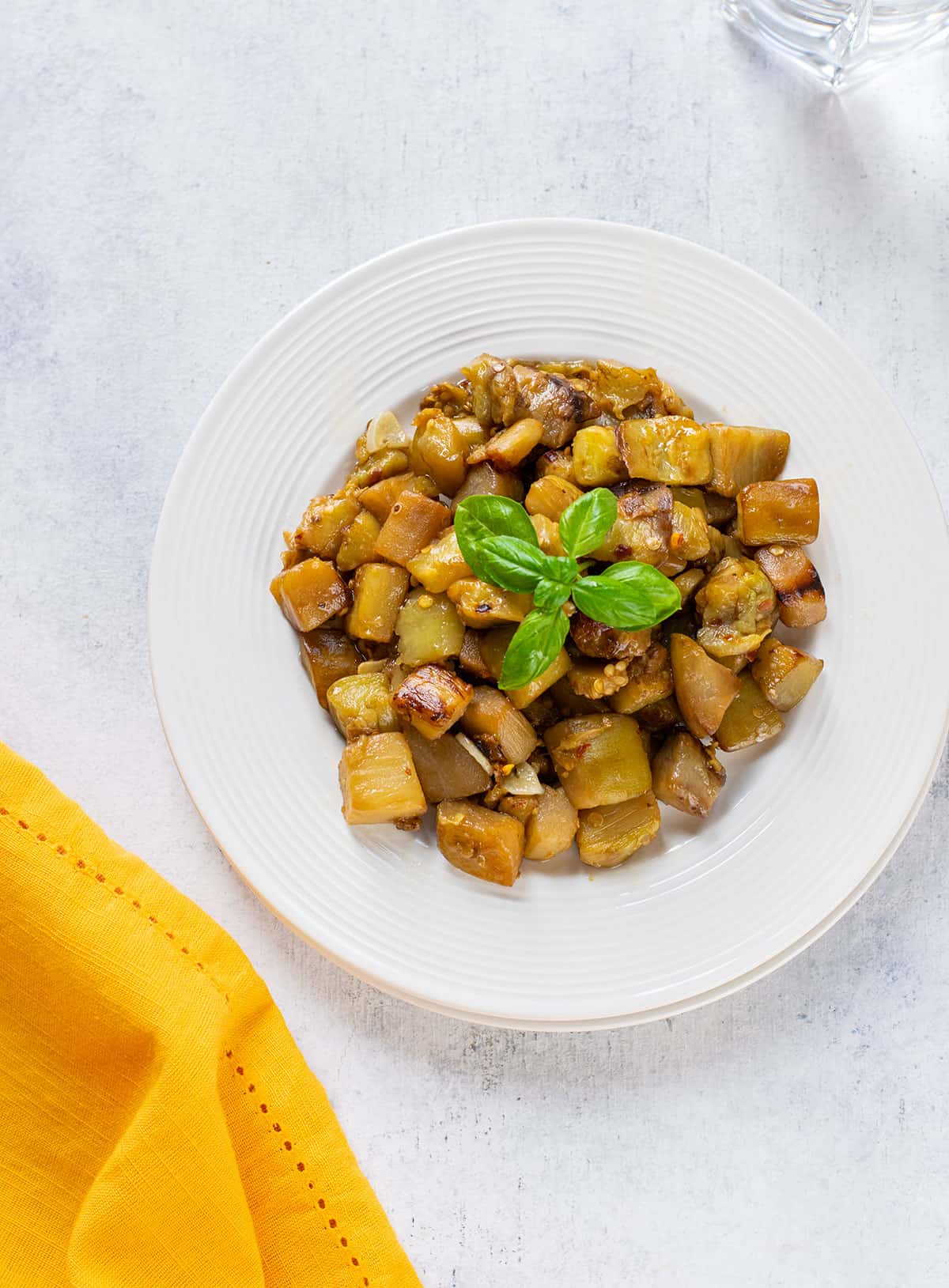 plate of sautéed eggplant cubes garnished with basil