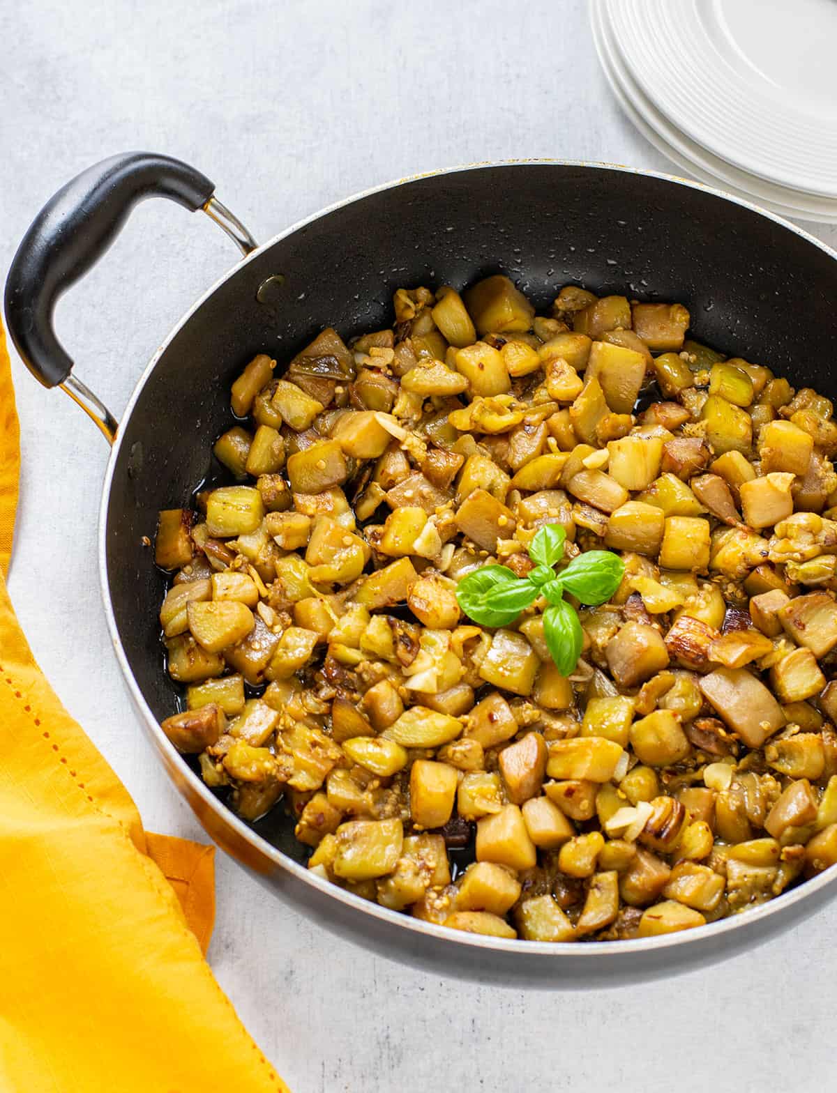 pan of sautéed eggplant cubes garnished with basil