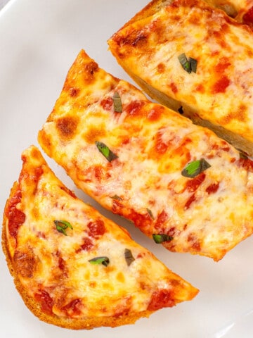 pizza made from italian bread on platter garnished with basil
