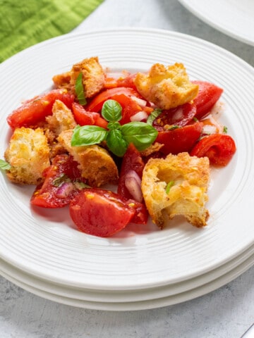 plate of bread and tomato salad garnished with basil leaves