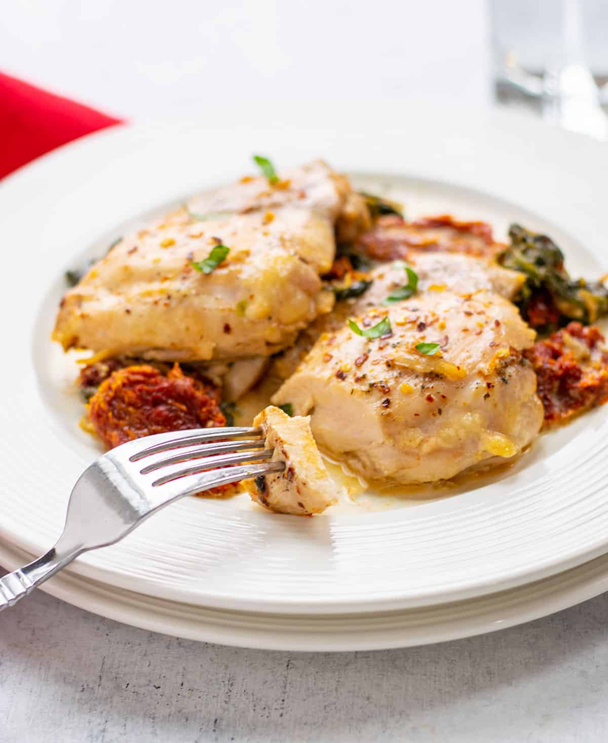 plate of chicken thighs with sun-dried tomato cream sauce garnished with basil