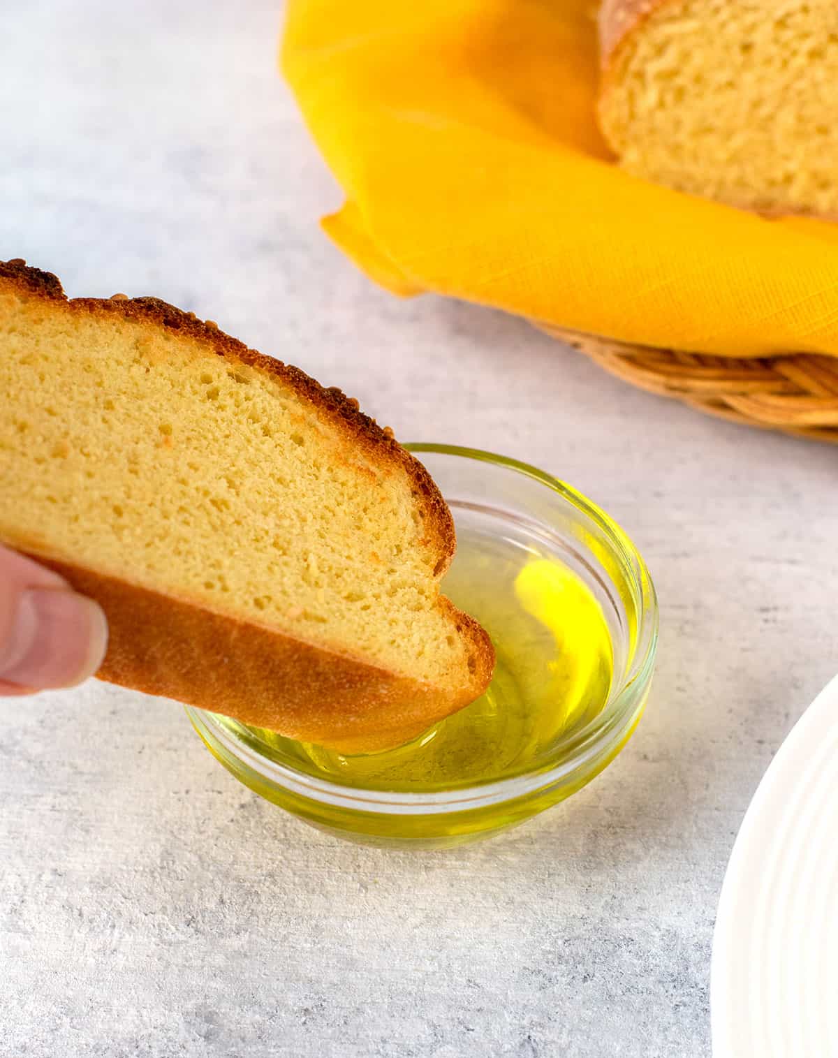 slice of italian semolina bread dipped in bowl of olive oil