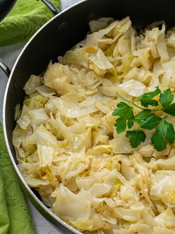 Sautéed cabbage in a pan garnished with parsley leaves