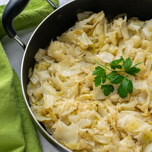 Sautéed cabbage in a pan garnished with parsley leaves
