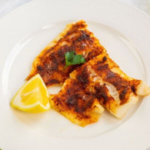 Plate of air fryer cod garnished with parsley and lemon wedge