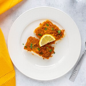 plate of cracker crusted cod garnished with parsley and lemon slices