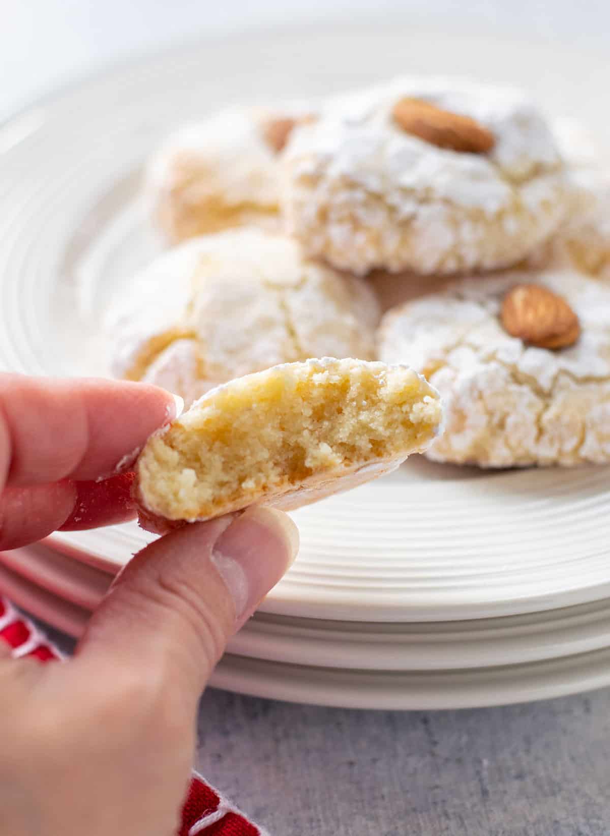 inside of an amaretti cookie held up in front of plate of cookies