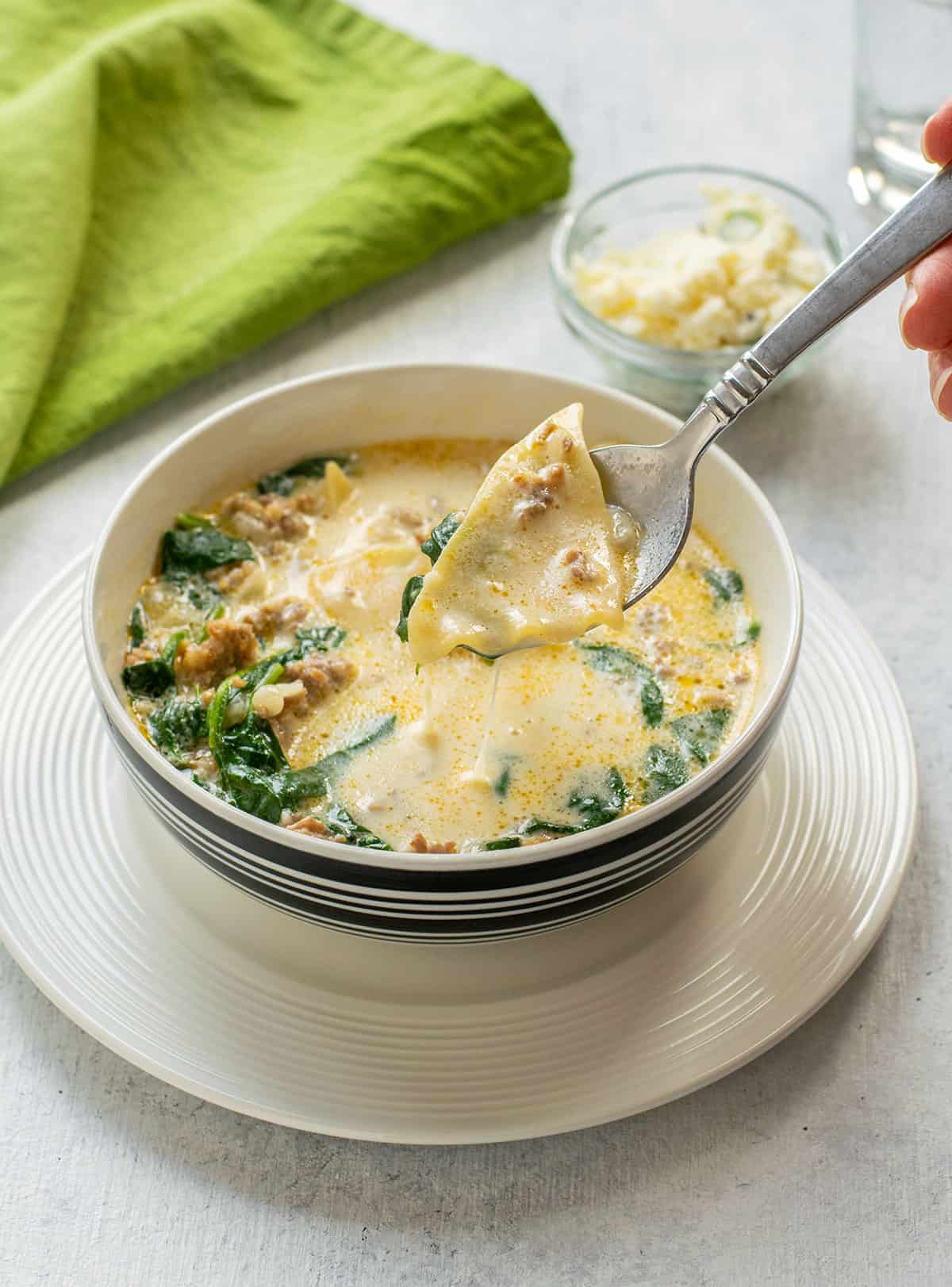 spoonful of white lasagna soup over a bowl