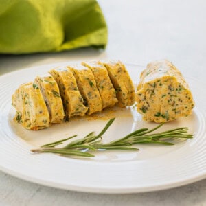 log of compound butter on a plate garnished with rosemary