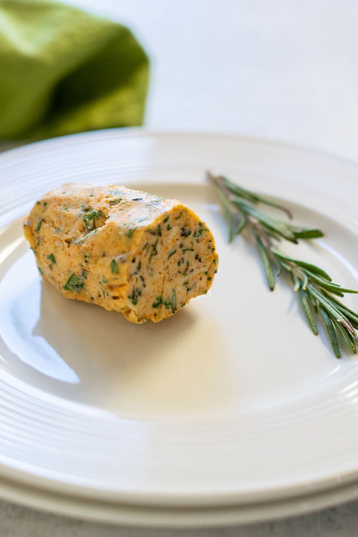 log of compound butter on a plate garnished with rosemary