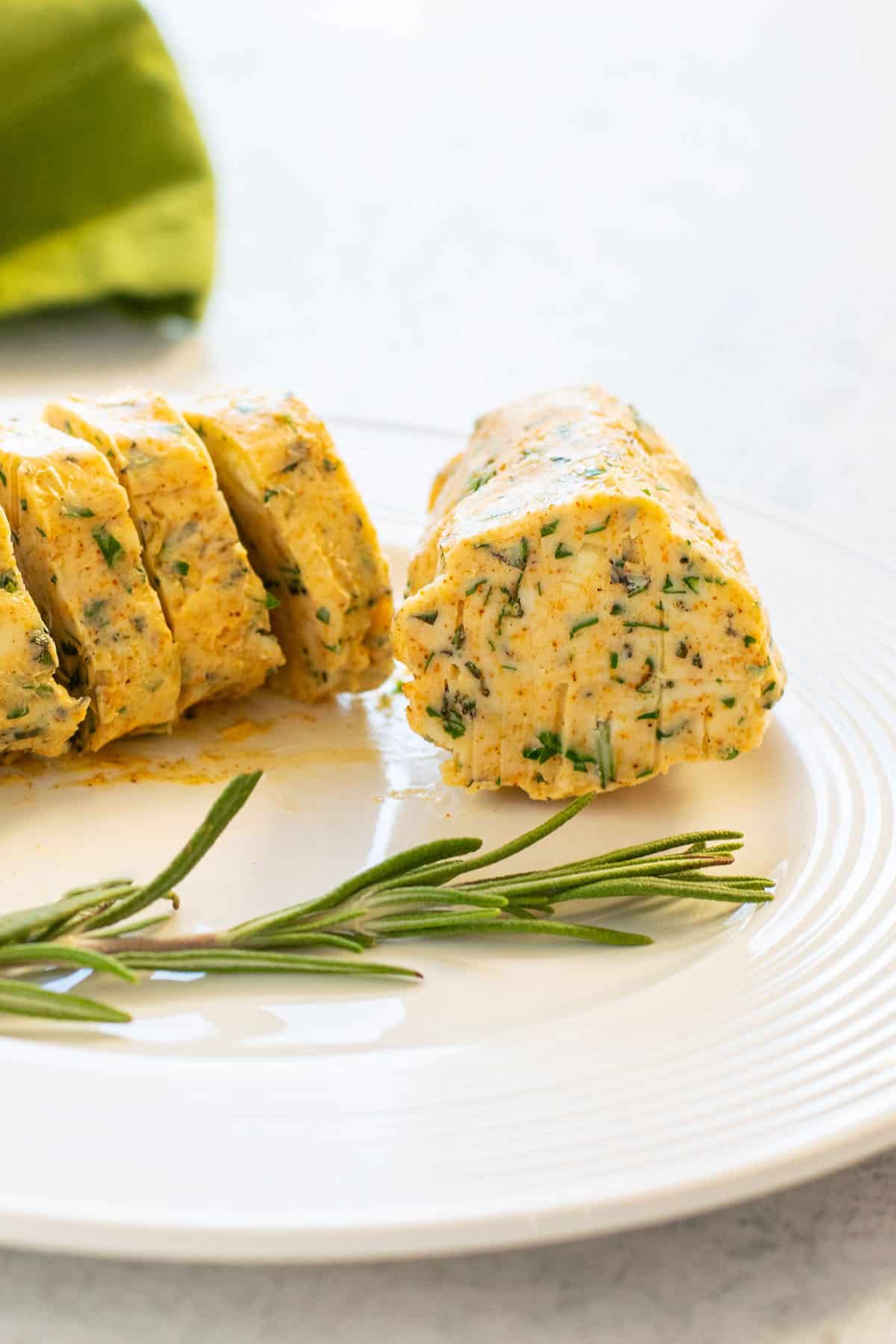 log of compound butter on a plate garnished with rosemary