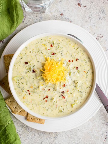 overhead bowl of broccoli cheddar soup topped with cheddar cheese