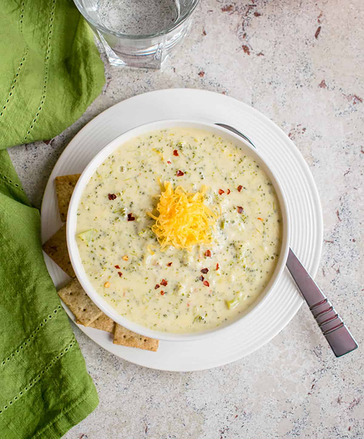 overhead bowl of broccoli cheddar soup topped with cheddar cheese