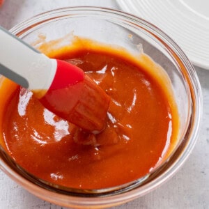 glass bowl of homemade bbq sauce with a silicone brush