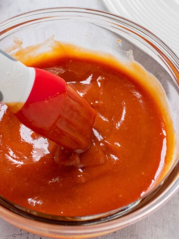 glass bowl of homemade bbq sauce with a silicone brush
