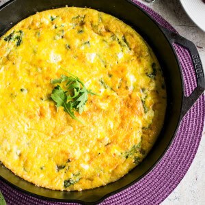 arugula frittata in cast iron pan garnished with arugula