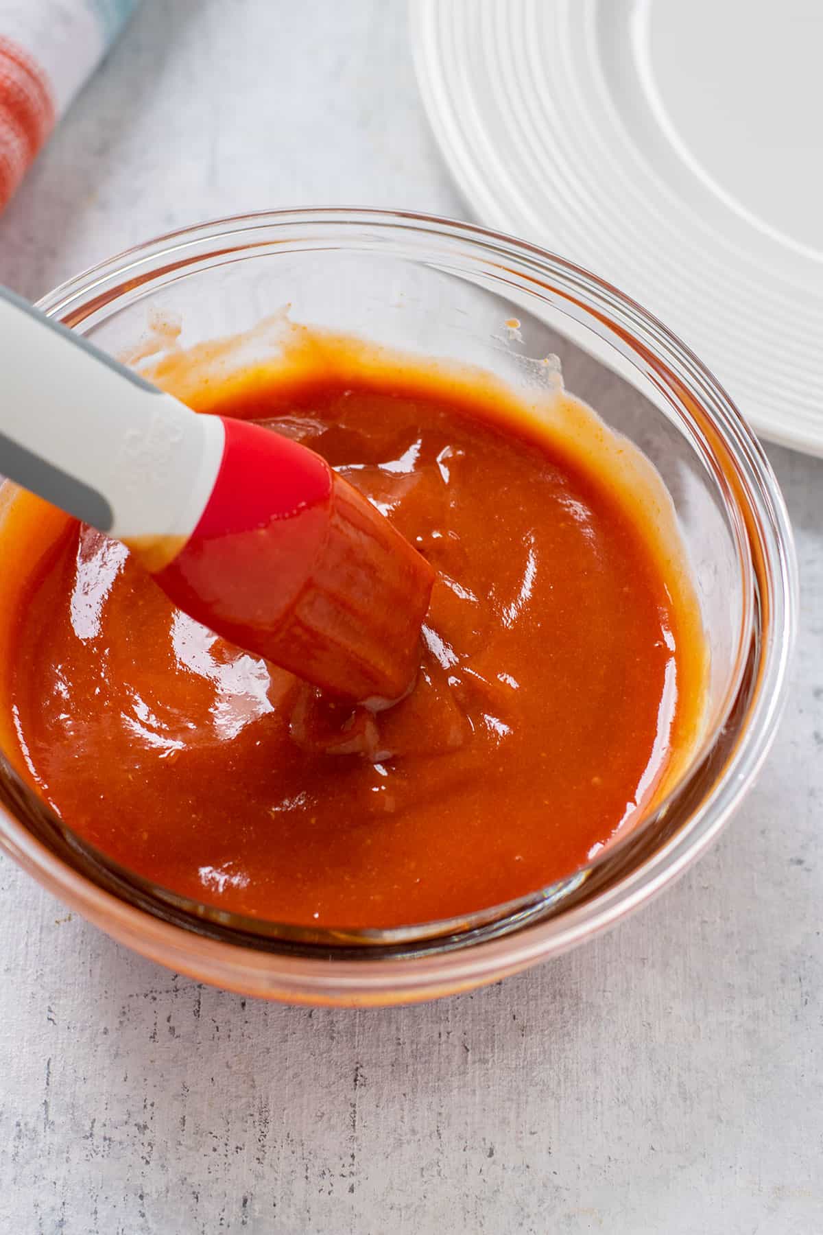 glass bowl of homemade bbq sauce with a silicone brush