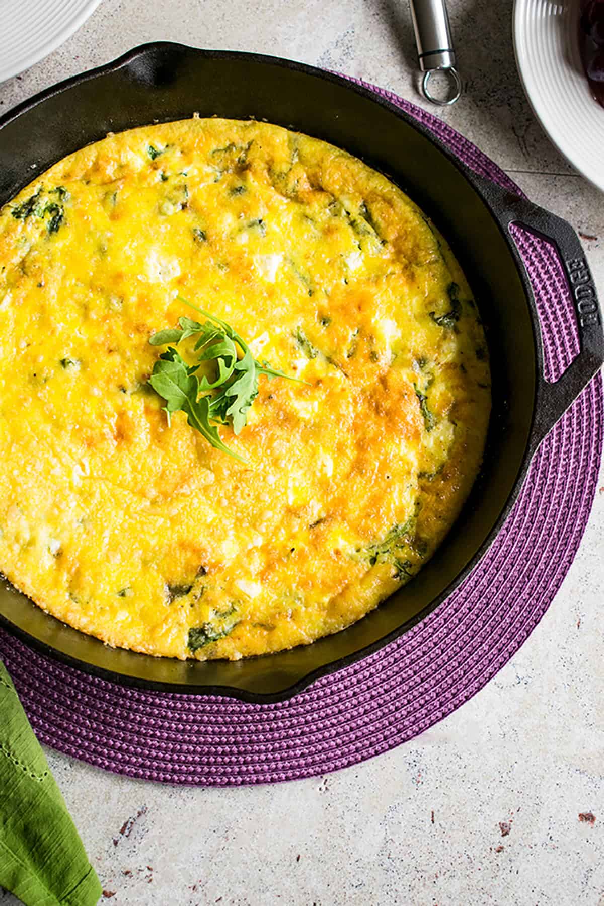 arugula frittata in cast iron pan garnished with arugula